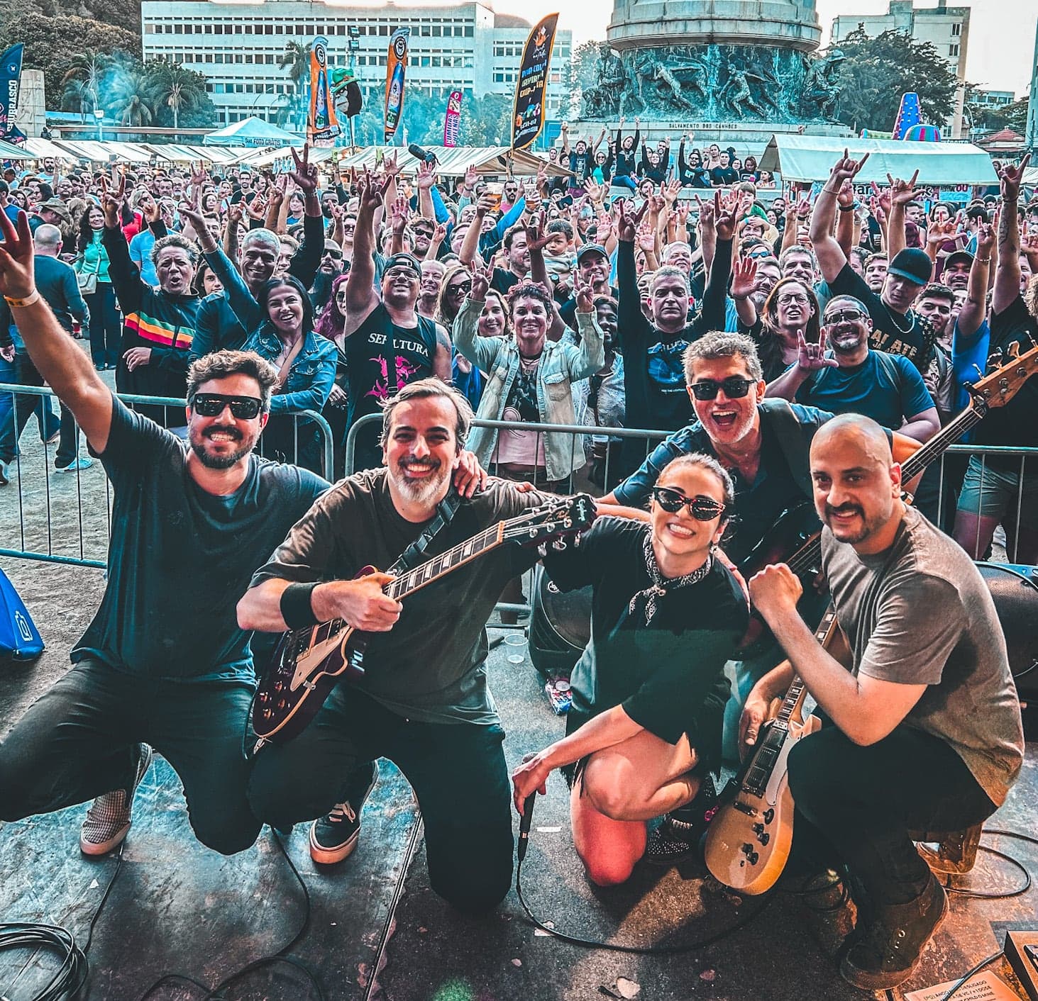 Foto da banda no palco com a plateia atrás
